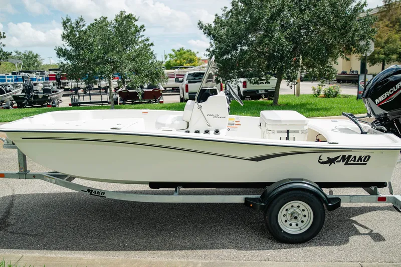 Slide: The Image of 2027 Mako Pro Skiff 15 CC boat on trailer, parked outdoors, with Mercury engine. - 5