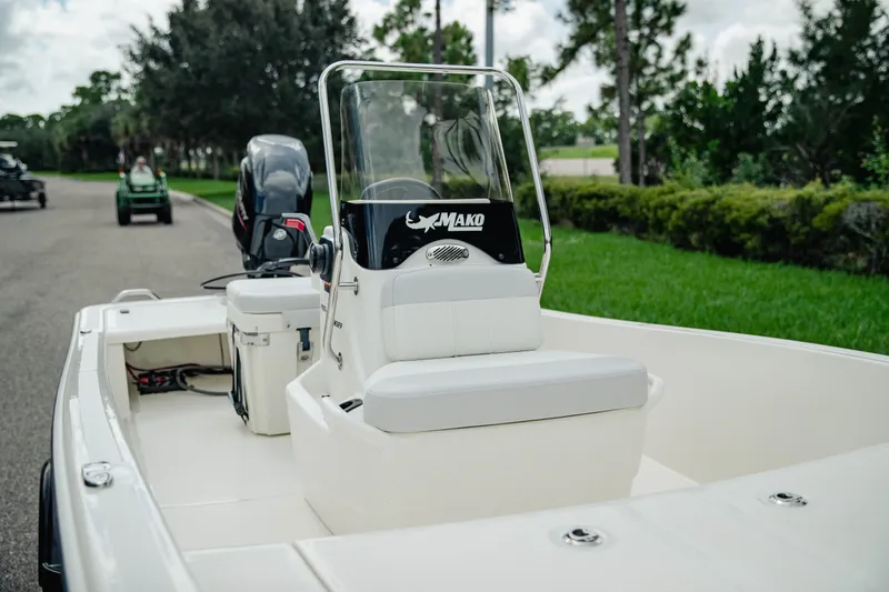 Slide: The Image of 2027 Mako Pro Skiff 15 CC boat with console and outboard motor on a scenic road. - 11