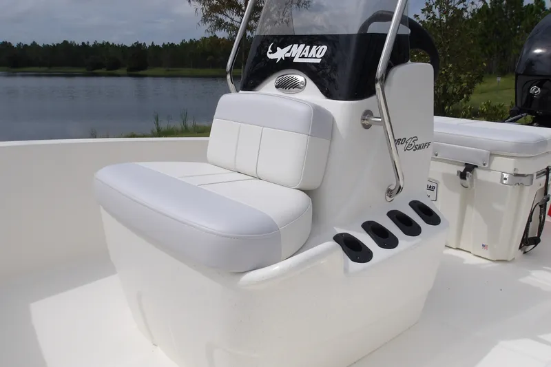 Slide: The Image of 2027 Mako Pro Skiff 15 CC boat with white seating and rod holders by a lake. - 10