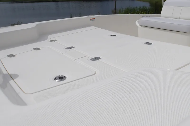 Slide: The Image of 2027 Mako Pro Skiff 15 CC boat deck with storage compartments, near water. - 9