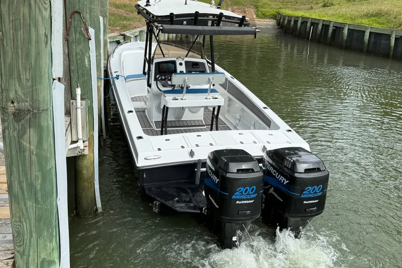 Slide: The Image of 1999 Blue Fin 260 Profish boat with dual Mercury 200 engines docked in water. - 2