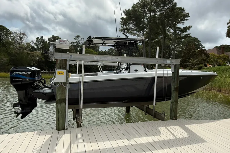 Slide: The Image of 1999 Blue Fin 260 Profish boat on lift, docked by a scenic waterfront. - 4