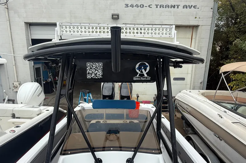 Slide: The Image of 1999 Blue Fin 260 Profish boat with T-top and QR code, parked at a service facility. - 15