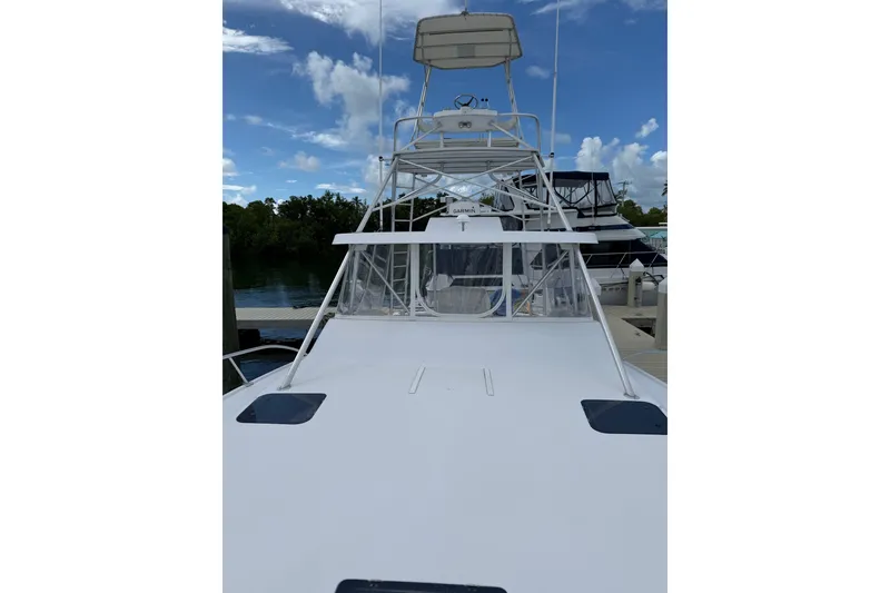 Slide: The Image of 1998 Luhrs 40 Open yacht docked, featuring a spacious deck and tower under a clear sky. - 34