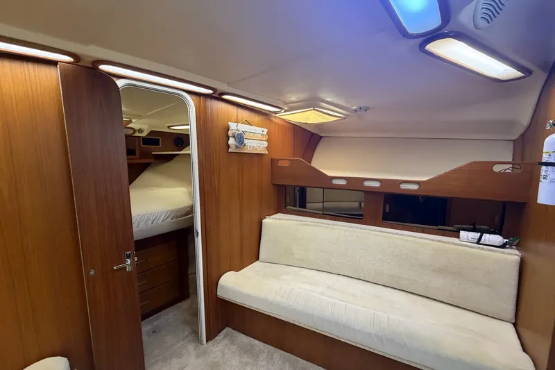Slide: The Image of 1998 Luhrs 40 Open cabin interior with wood paneling and beige seating. - 15