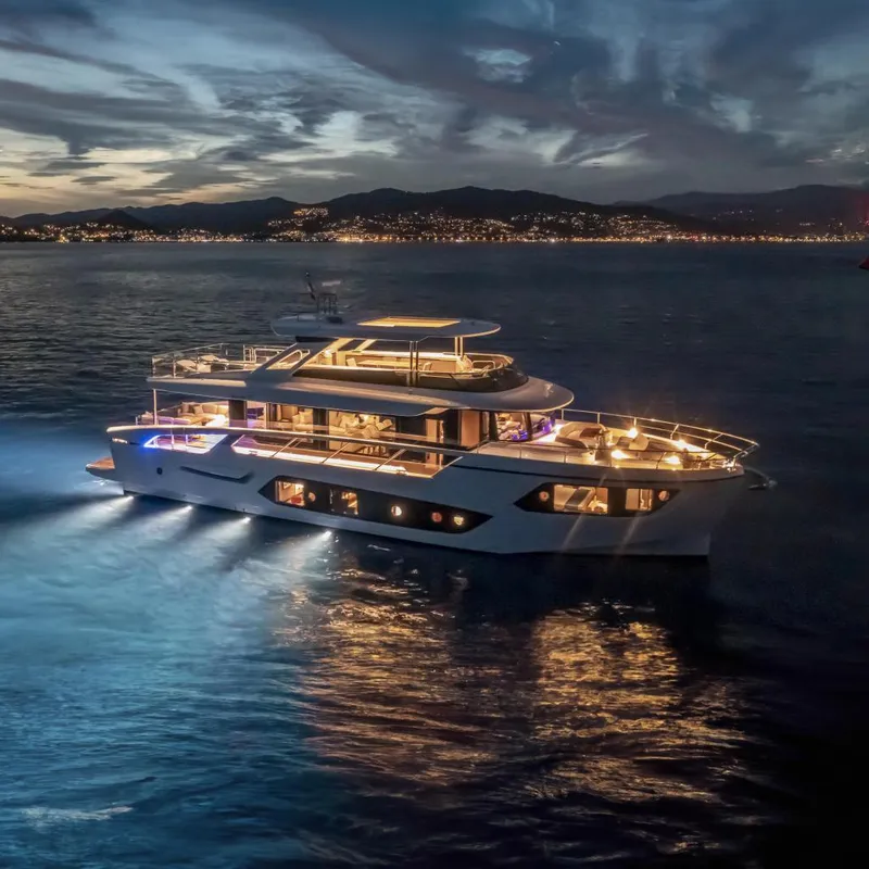Slide: The Image of Luxurious 2025 Absolute NAVETTA 75 yacht illuminated at night on serene waters. - 0