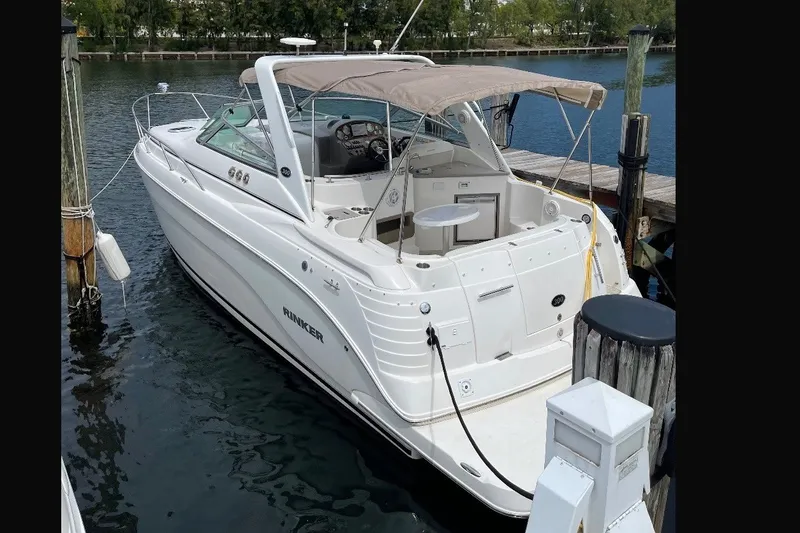 Slide: The Image of 2009 Rinker 300 Express Cruiser docked at marina, featuring sleek design and spacious deck. - 2