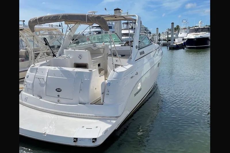 Slide: The Image of 2009 Rinker 300 Express Cruiser docked in a marina under clear blue skies. - 1