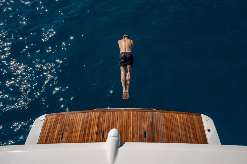 Slide: The Image of Man diving off Absolute Navetta 58 yacht into sparkling blue sea, 2026 model. - 12