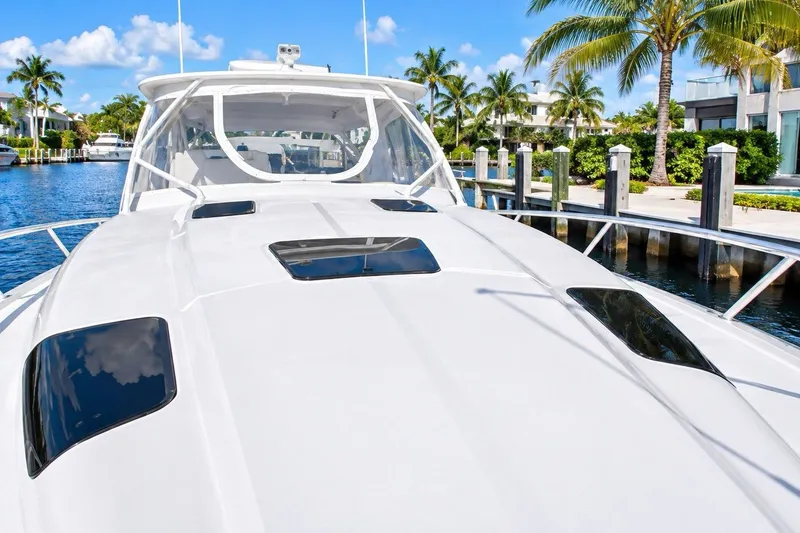Slide: The Image of 2022 Intrepid 477 Evolution yacht docked by palm trees and waterfront homes. - 1