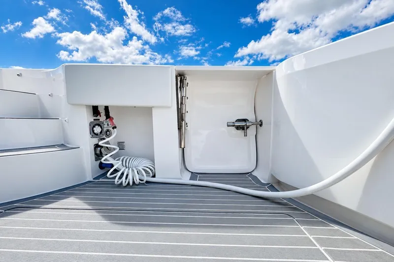 Slide: The Image of 2022 Intrepid 477 Evolution boat deck with hose and storage compartment under blue sky. - 10