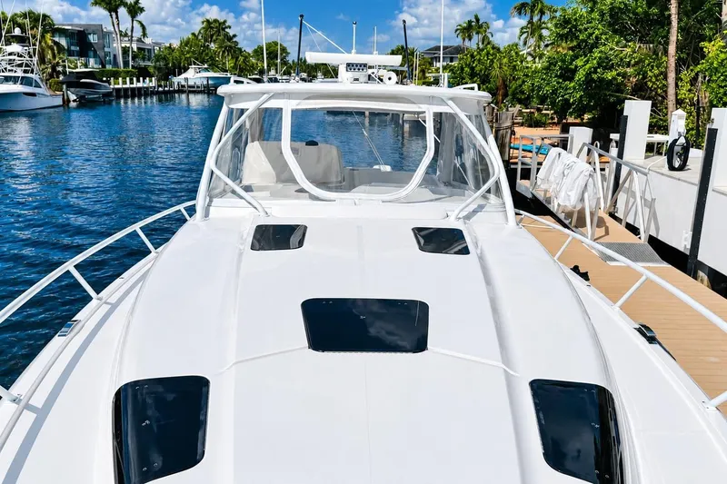 Slide: The Image of 2022 Intrepid 477 Evolution yacht docked by a scenic waterfront. - 6
