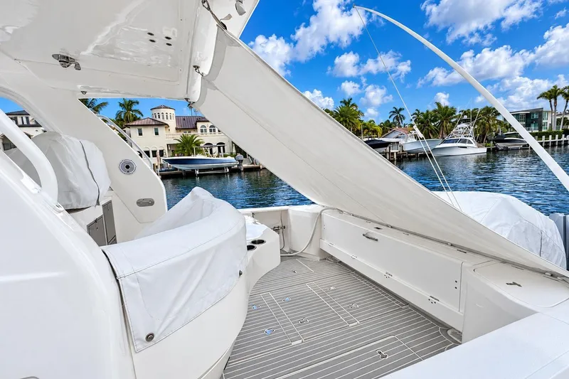 Slide: The Image of 2022 Intrepid 477 Evolution yacht deck with seating, docked by waterfront homes. - 7