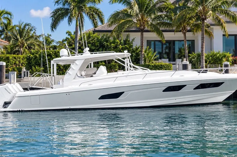 The Image of 2022 Intrepid 477 Evolution yacht docked near a luxurious waterfront home. - 0