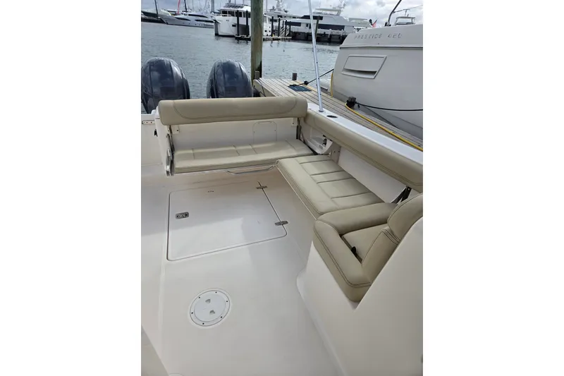 Slide: The Image of 2017 Pursuit DC 265 Dual Console boat interior with beige seating, docked at marina. - 14