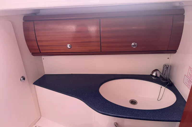 Slide: The Image of Interior of 2003 Bavaria Cruiser 44 yacht, featuring a wooden cabinet and sleek sink area. - 31
