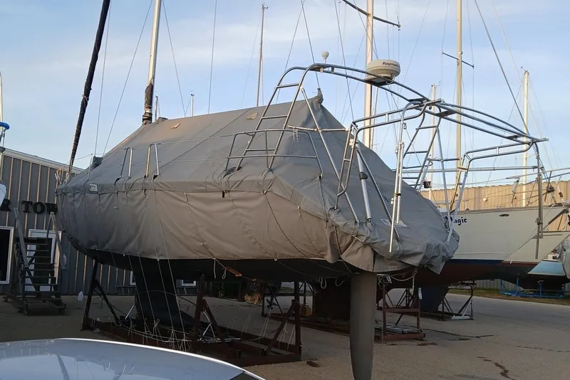 Slide: The Image of Covered 2003 Bavaria Cruiser 44 sailboat in a marina, surrounded by other boats. - 38