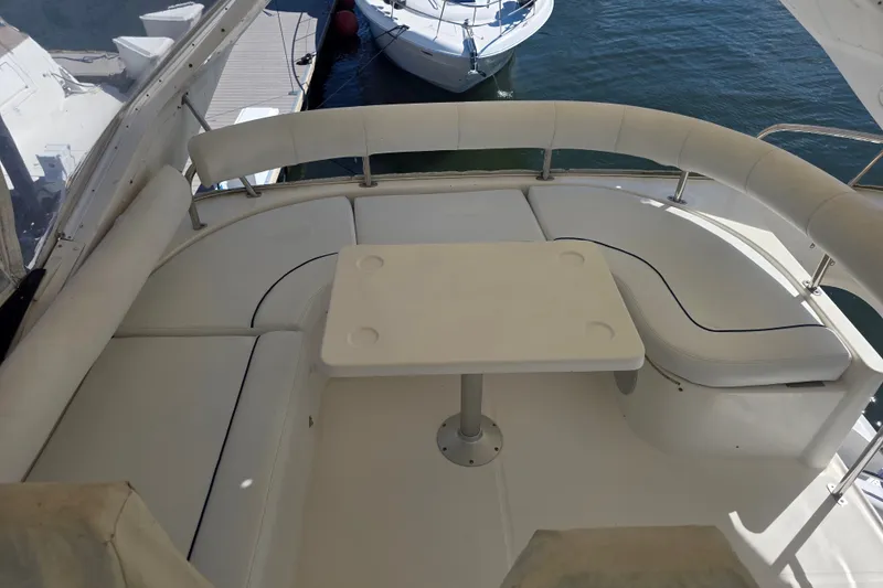 Slide: The Image of Flybridge seating area on a 2002 Neptunus 56 yacht, featuring a white table and cushioned seats. - 11