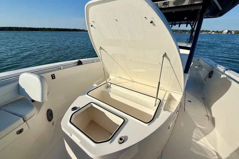 Slide: The Image of 2023 Cobia 350 Center Console boat with open storage compartment on calm water. - 23
