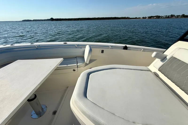 Slide: The Image of 2023 Cobia 350 Center Console boat interior with seating and table, overlooking calm waters. - 21