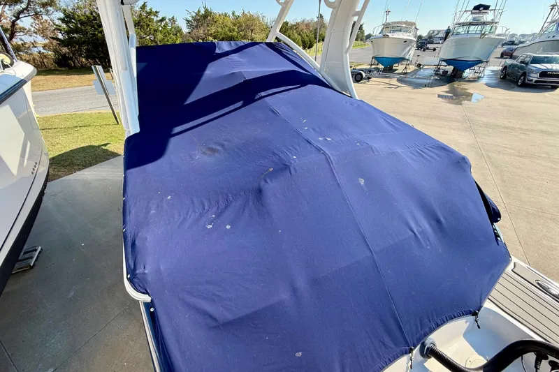 Slide: The Image of 2021 Chaparral 280 OSX boat covered with a blue tarp in a marina setting. - 34
