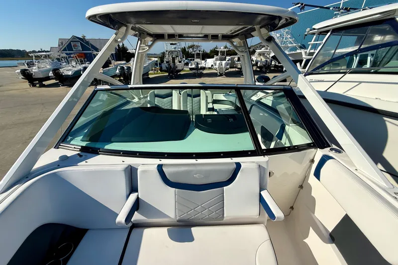 Slide: The Image of 2021 Chaparral 280 OSX boat interior with seating and windshield, docked at marina. - 16