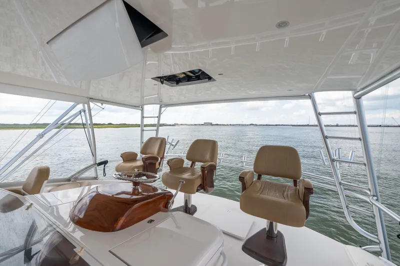 Slide: The Image of Flybridge of 2014 Viking 70C yacht with helm chairs overlooking serene waters. - 36