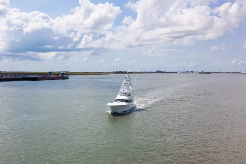 Slide: The Image of 2014 Viking 70C yacht cruising on a calm waterway under a partly cloudy sky. - 12