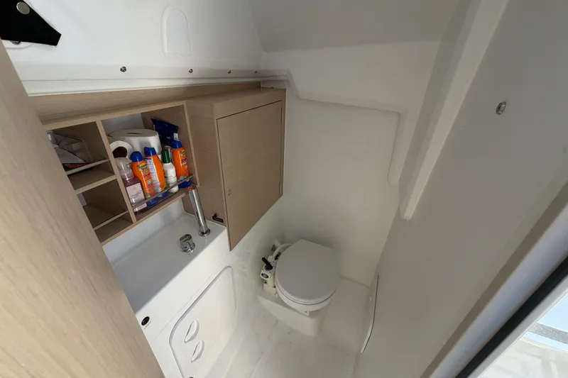 Slide: The Image of Beneteau Oceanis 30.1 2021 yacht bathroom with sink, toilet, and storage shelves. - 13