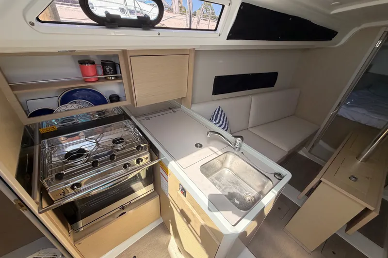 Slide: The Image of Interior of 2021 Beneteau Oceanis 30.1 yacht, featuring kitchen and seating area. - 11