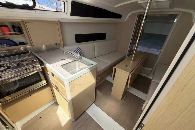 Slide: The Image of Interior of 2021 Beneteau Oceanis 30.1 yacht, featuring a compact kitchen and cozy seating area. - 15