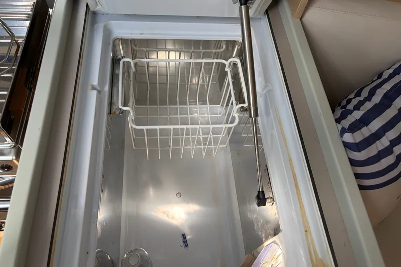 Slide: The Image of Open refrigerator compartment on 2021 Beneteau Oceanis 30.1 yacht, featuring wire basket storage. - 21