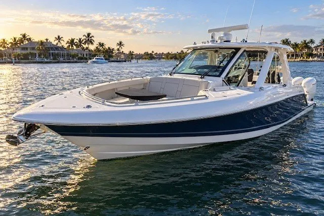 The Image of 2019 Boston Whaler 380 Realm boat on water at sunset, near palm-lined shore. - 0