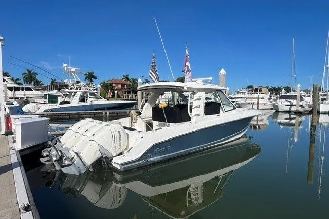 Slide: The Image of 2019 Boston Whaler 380 Realm boat docked in a marina under clear blue skies. - 1