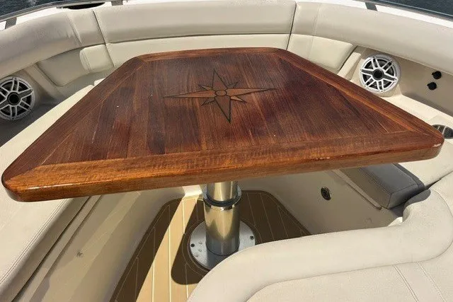 Slide: The Image of 2019 Boston Whaler 380 Realm boat interior with wooden table and cushioned seating. - 15