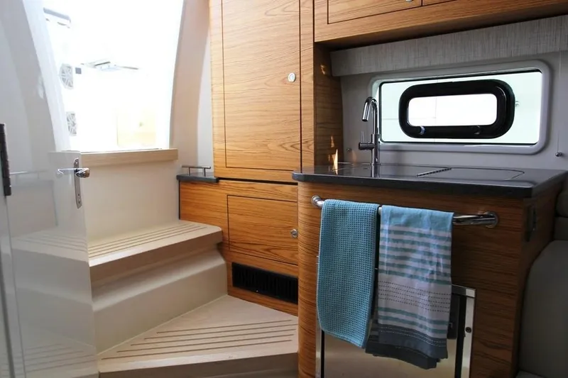 Slide: The Image of Manufacturer Provided Image: Interior of 2019 Boston Whaler 380 Realm with wooden cabinetry and compact kitchen. - 7