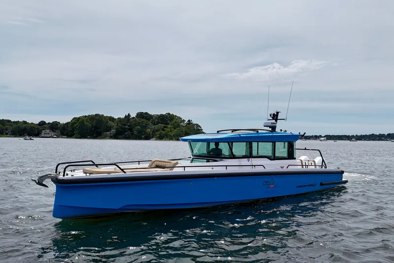 Slide: The Image of 2021 Axopar 37 XC Cross Cabin boat on water, blue exterior, scenic background. - 1