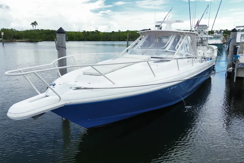 Slide: The Image of 2001 Intrepid 377 Walkaround boat docked in calm waters, featuring a sleek blue hull. - 8