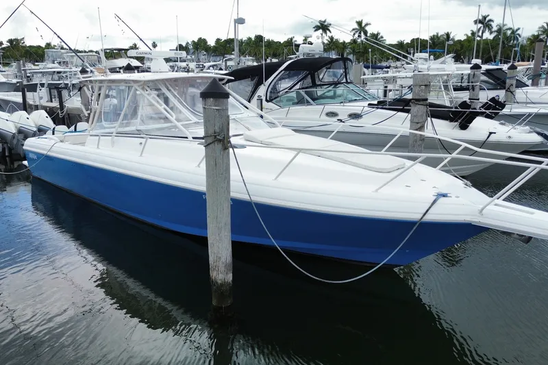 Slide: The Image of 2001 Intrepid 377 Walkaround boat docked in a marina, featuring a sleek blue and white design. - 6