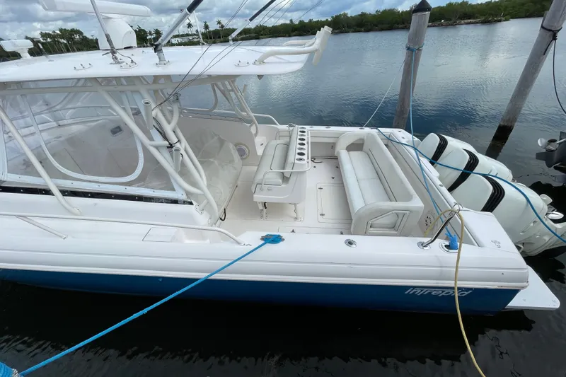Slide: The Image of 2001 Intrepid 377 Walkaround boat docked, featuring spacious seating and dual outboard motors. - 25
