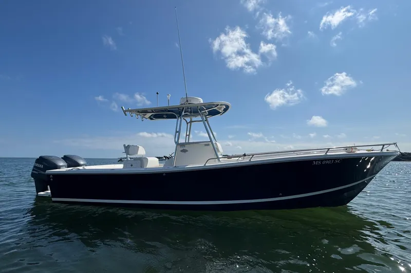 Slide: The Image of A 2006 Regulator 26 Forward Seating boat on calm water under a blue sky. - 2