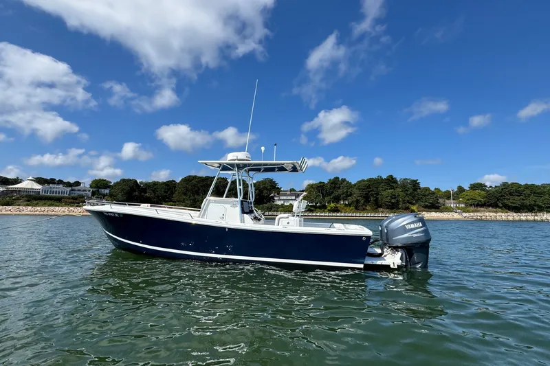 Slide: The Image of 2006 Regulator 26 Forward Seating boat on calm water under blue sky. - 0