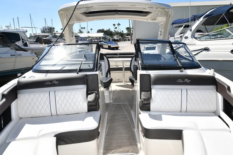 Slide: The Image of 2017 Sea Ray SLX 310 boat interior with white seating and sleek design at a marina. - 31
