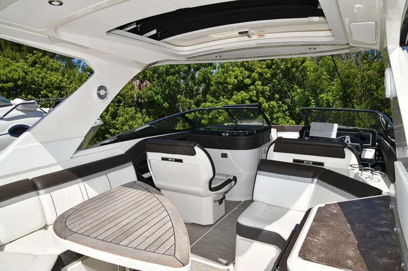 Slide: The Image of 2017 Sea Ray SLX 310 boat interior with seating and table, surrounded by lush greenery. - 40
