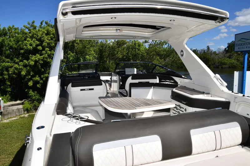 Slide: The Image of 2017 Sea Ray SLX 310 boat interior with seating and table, docked near lush greenery. - 38