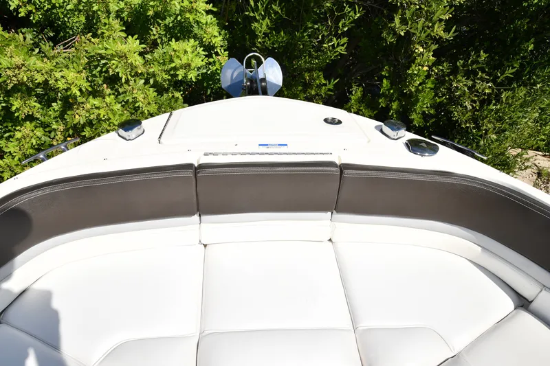 Slide: The Image of 2017 Sea Ray SLX 310 boat bow with cushioned seating and lush greenery background. - 23