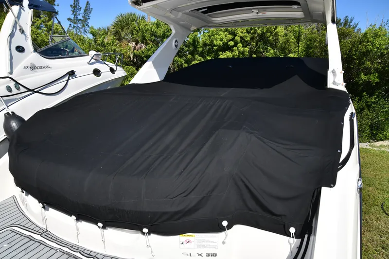 Slide: The Image of 2017 Sea Ray SLX 310 boat with black cover, docked outdoors. - 19