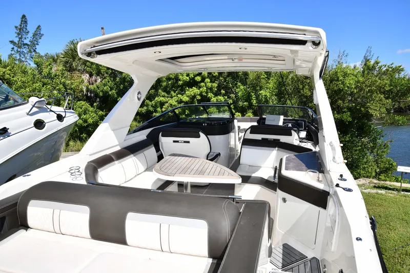Slide: The Image of 2017 Sea Ray SLX 310 boat interior with seating and table, surrounded by lush greenery. - 35