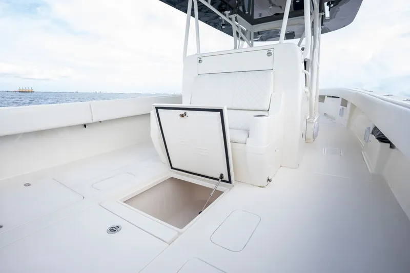 Slide: The Image of 2017 SeaVee 390Z boat deck with open storage compartment, white seating, and ocean view. - 38