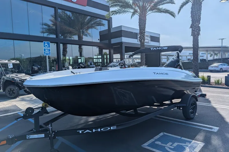 Slide: The Image of 2027 Tahoe T18 boat on trailer in parking lot, near palm trees and building. - 2